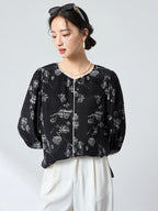 Side profile of a black printed silk blouse showcasing the flowy silhouette and three-quarter puff sleeves, crafted from 100% mulberry silk.