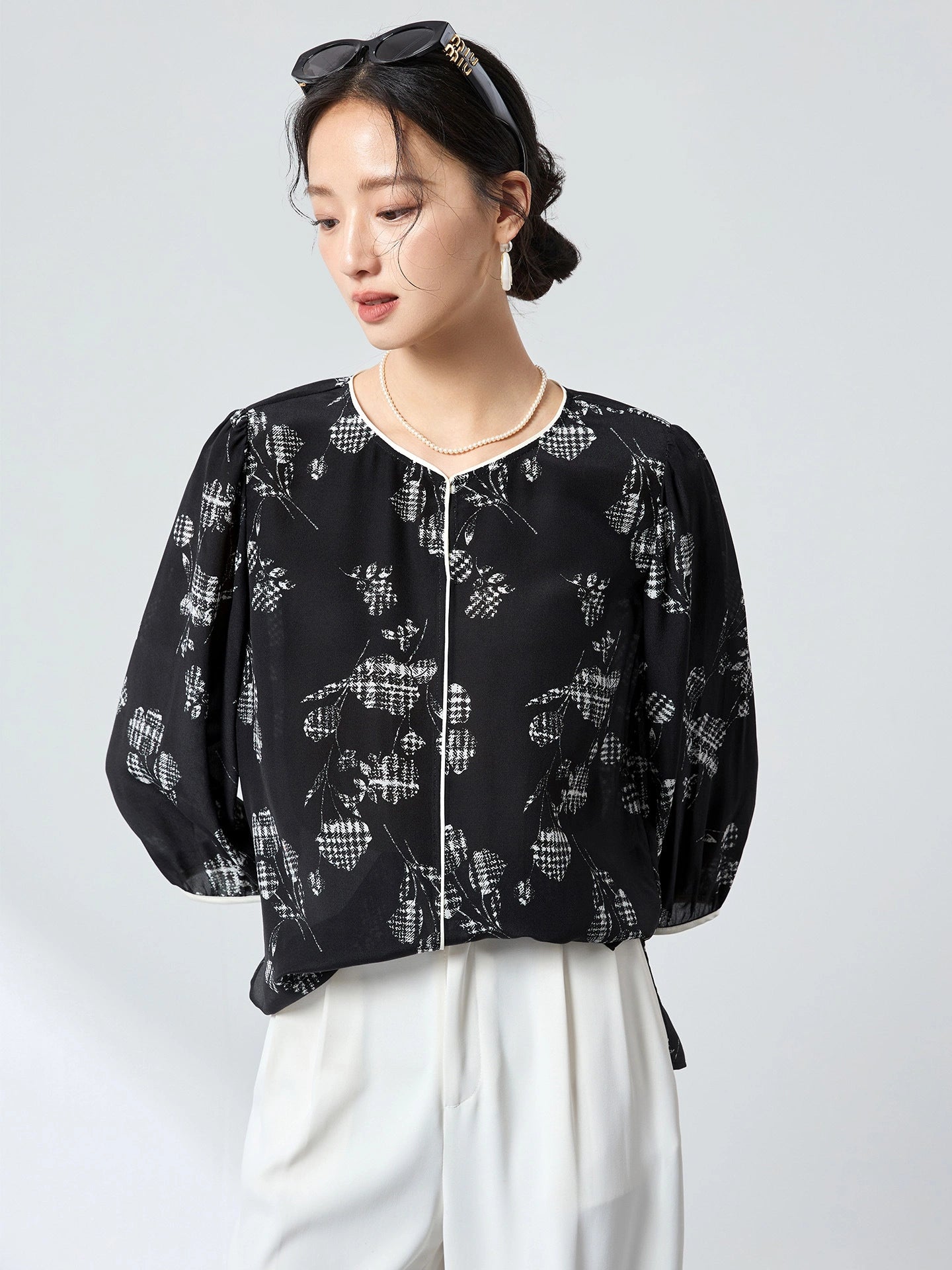 Side profile of a black printed silk blouse showcasing the flowy silhouette and three-quarter puff sleeves, crafted from 100% mulberry silk.