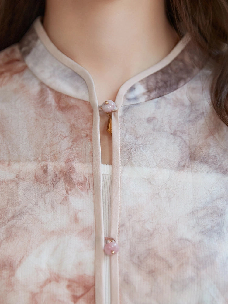 Close-up of a 100% mulberry silk blouse featuring a delicate stand collar, pink bead buttons, and a unique watercolor tie-dye print.