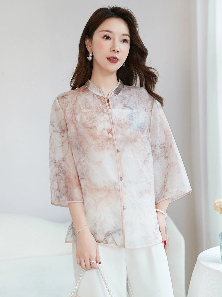 Model wearing a 100% silk New Chinese style top with a stand collar and three-quarter sleeves, featuring a beautiful pink and grey watercolor pattern, paired with white trousers.
