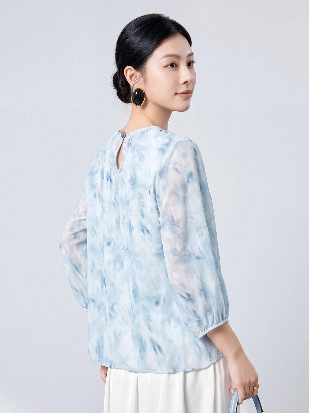 Back view of the sky blue mulberry silk blouse with a round neck and keyhole button closure