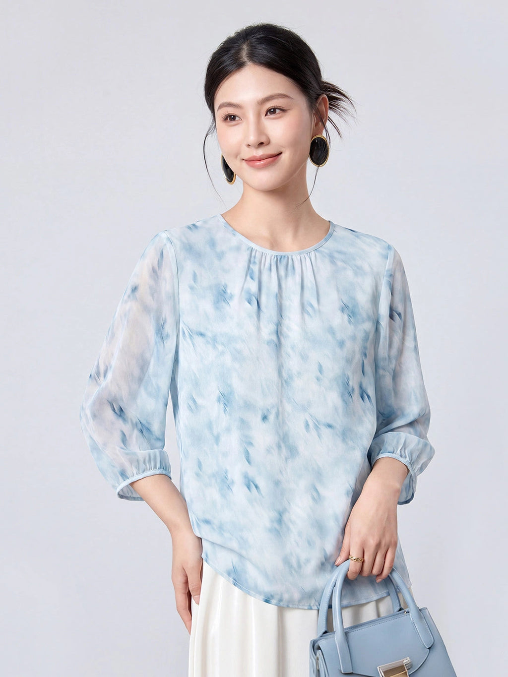 Woman wearing a sky blue printed mulberry silk blouse with a round neck and three-quarter sleeves