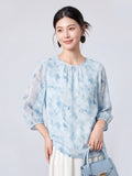 Woman wearing a sky blue printed mulberry silk blouse with a round neck and three-quarter sleeves