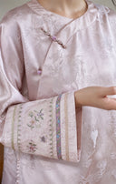 Close-up of a floral embroidered cuff beside the jacket’s asymmetric front and decorative closures.