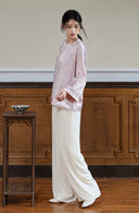 Side view of a model wearing the smoky pink jacquard jacket with embroidered cuffs and ivory wide-leg trousers.