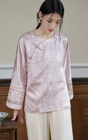 Upper-body view of the smoky pink jacket showing its round neckline, jacquard pattern and wide embroidered cuffs.
