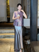 Model wearing a smoky purple satin maxi skirt paired with a purple embroidered vest, holding a decorative fan, highlighting the versatile styling.