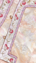 Macro view of the vest’s berry embroidery, jacquard texture, lilac piping and decorative buttons.