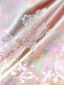Close-up of lustrous pink-gold jacquard fabric with pale floral motifs.