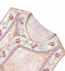 Close-up of the pink-gold vest neckline with berry and blossom embroidery, lilac trim and decorative buttons.