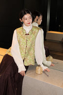 Closer view of the vest’s V-neck, single-row buttons and floral brocade pattern