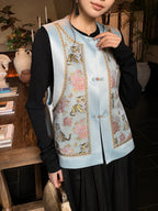 Close-up of a light blue Songjin silk Chinese vest with round collar, floral and tiger motifs, and traditional button closure.