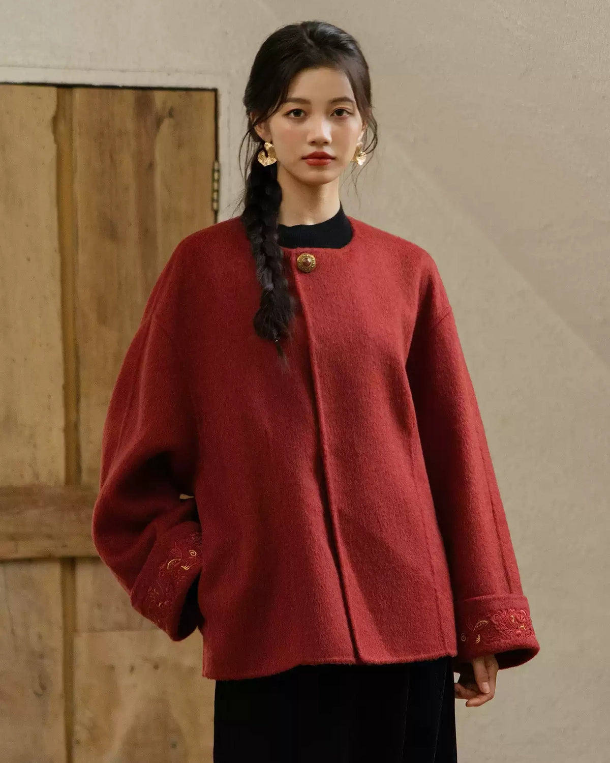 Front view of the Suian crimson red coat showing its round neckline, relaxed shape, and embroidered cuffs