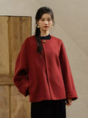 Front view of the Suian crimson red coat showing its round neckline, relaxed shape, and embroidered cuffs