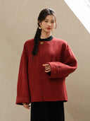 Close view of the Suian coat showing its textured red fabric, decorative neckline accent, and embroidered cuff