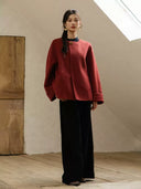 Full-length view of the crimson red coat showing its roomy sleeves, straight hem, and embroidered turn-up cuffs