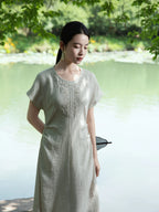 Woman wearing a relaxed embroidered maxi dress by the lakeside in a light sage summer outfit