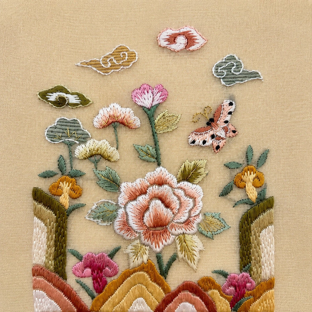Close-up of colorful Suzhou-style floral and butterfly embroidery on champagne yellow silk
