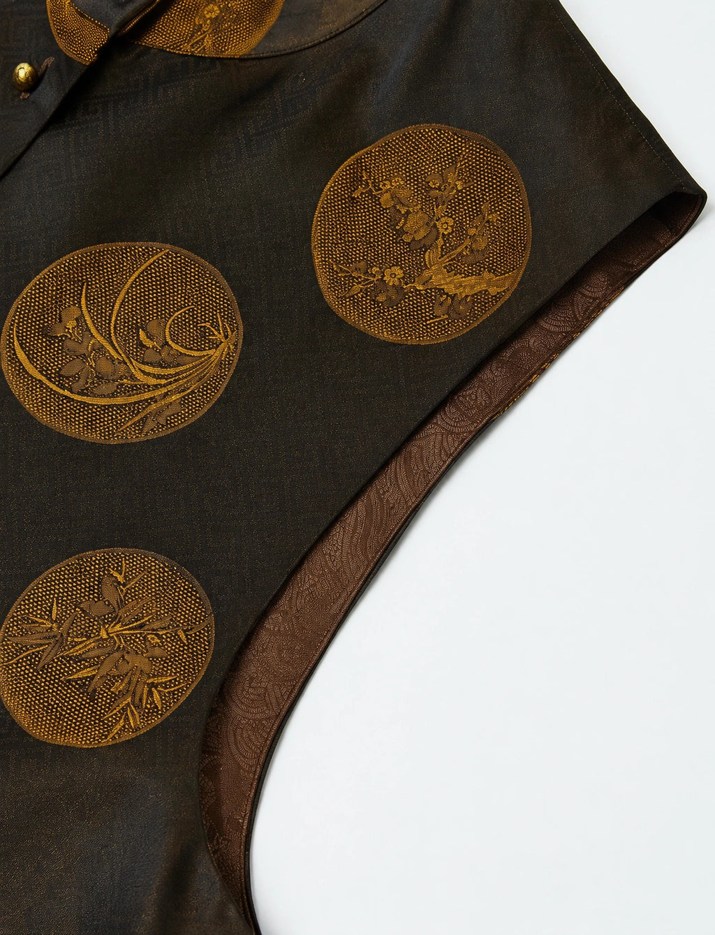 Close-up of a brown-black garment with gold circular floral medallions and patterned lining