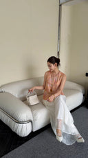 Model sitting on a white sofa in a Qipao-style vest top, showcasing the elegant relaxed fit and Mandarin collar with textured jacquard fabric.