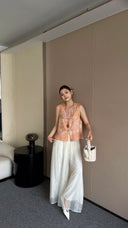 Side view of a women's sleeveless Cheongsam top featuring traditional frog buttons and intricate floral batik print, styled with white trousers.