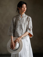 Woman wearing a Warm Mist jacquard Mandarin collar blouse with a white skirt.