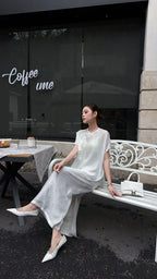 Model sitting on a white bench in a white New Chinese style co-ord set, highlighting the side slit detail on the skirt and the breathable fabric.