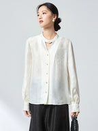 Front view of a white stand-collar blouse with button-down front and delicate jacquard pattern, paired with a black skirt, crafted from 75.2% Viscose and 24.8% Mulberry Silk.