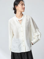 Model wearing a white long-sleeve jacquard blouse with a stand collar, featuring a relaxed fit and subtle floral pattern, perfect for a refined New Chinese look.