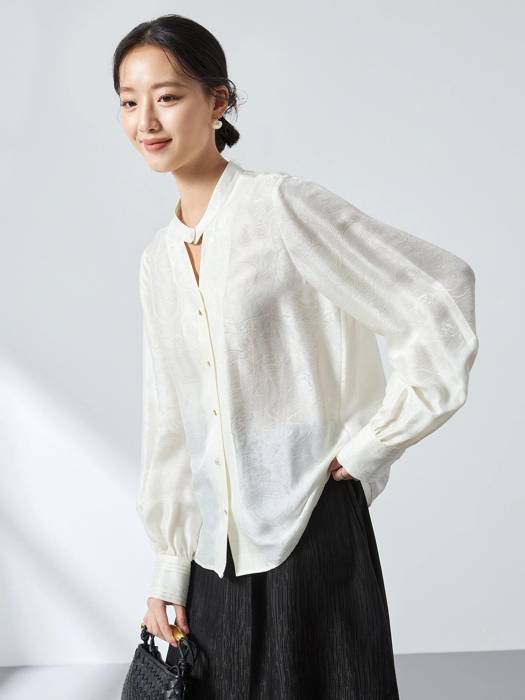 Side view of a white jacquard blouse with a stand collar and relaxed fit, highlighting the elegant drape and versatile styling.