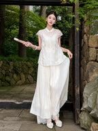 Side view of a white Cheongsam top with lace details, paired with white trousers and pearl shoes, highlighting the relaxed silhouette.