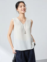 Model wearing a white V-neck sleeveless silk blend vest, holding a black handbag, highlighting the elegant drape of the 41.1% Mulberry Silk fabric.