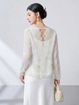 Back view of a white sheer silk top featuring intricate butterfly embroidery, lace panels, and a delicate lace-up criss-cross back detail.