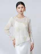 Front view of a women's white 100% silk top with a round neckline, sheer fabric, and delicate butterfly embroidery, paired with a white satin skirt.