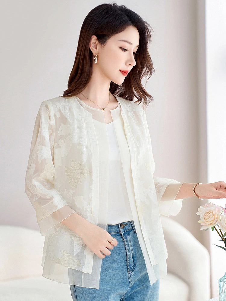 Model wearing a white semi-sheer silk cardigan over a tank top and blue jeans, holding a rose, showcasing the elegant and versatile look.
