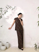 Model leaning against a wall wearing a wine red silk wide-leg pantsuit set with a mandarin collar top and side buttons, showcasing the luxurious drape of 100% silk fabric.