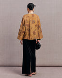 Back view of an antique gold silk jacket with embroidered flowers and deer