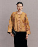 Woman wearing an antique gold floral and deer embroidered silk jacket with a black skirt