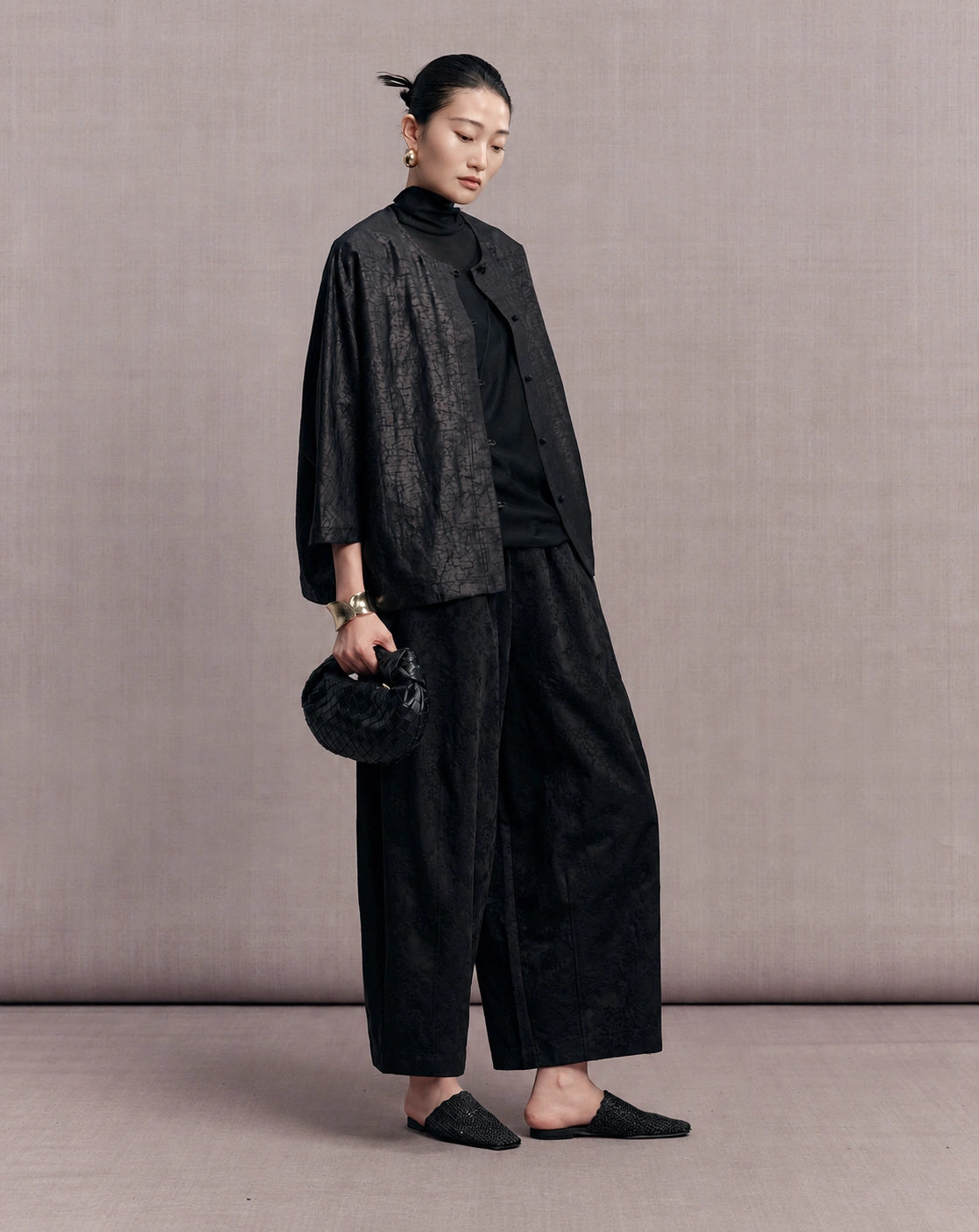 Side view of the black crackle-pattern jacket styled with wide-leg trousers