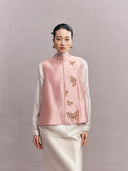Woman wearing a blush pink silk and wool vest with butterfly embellishments over a white blouse