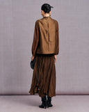 Back view of the bronze brown sleeveless vest styled over a long-sleeve top