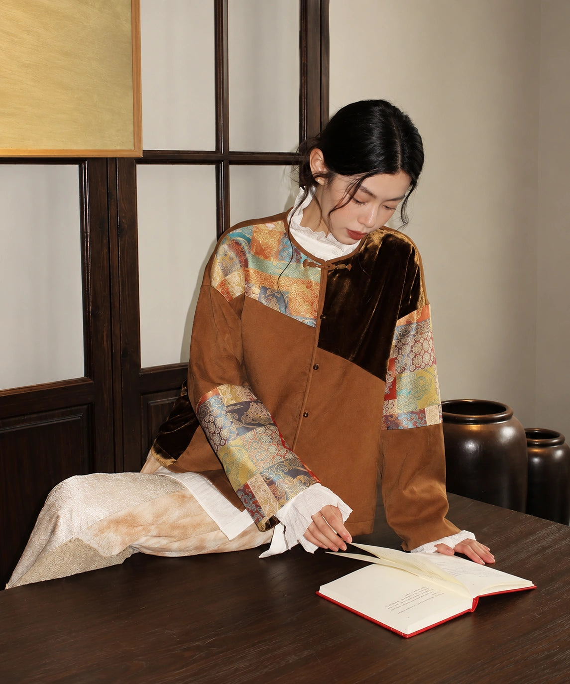 Woman wearing the brown patchwork jacket while seated, showing its colorful sleeves