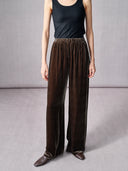 Full-length view of dark brown silk velvet wide-leg pants styled with a black sleeveless top