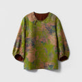Front view of a green floral Xiangyunsha silk blouse with a round neck, asymmetric button closure and three-quarter sleeves