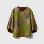 Front view of a green floral Xiangyunsha silk blouse with a round neck, asymmetric button closure and three-quarter sleeves