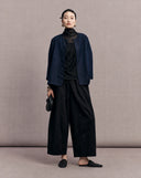 Full-length view of the navy side of the reversible jacket styled with black trousers
