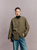 Woman wearing an olive green New Chinese jacket with a round neckline, frog buttons and patch pockets