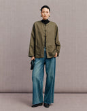 Full-length front view of the olive green New Chinese jacket styled with blue wide-leg jeans