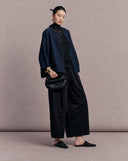 Navy side of the reversible silk jacket styled with a black top and wide-leg trousers