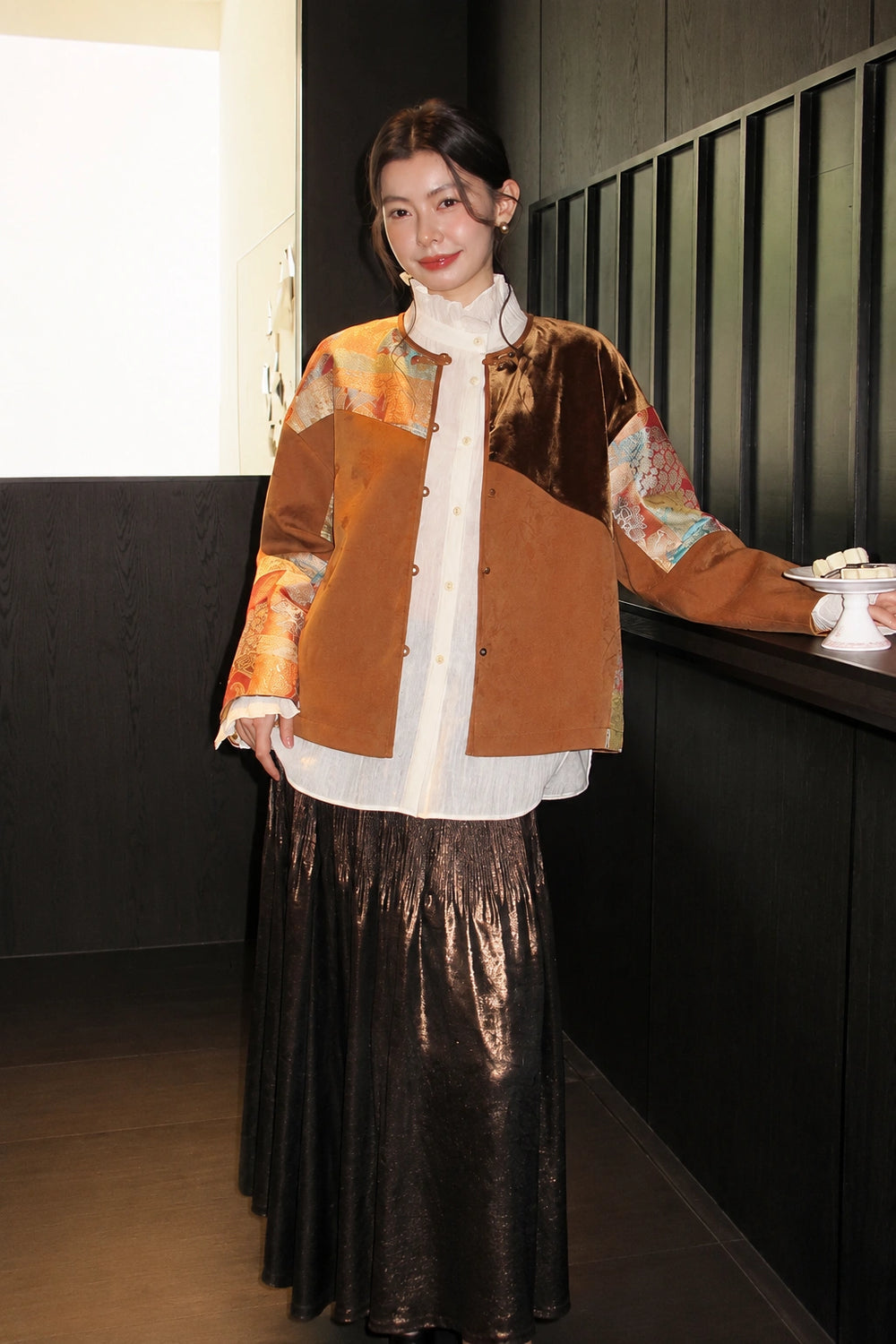 Front view of the brown patchwork jacket worn open over a white blouse